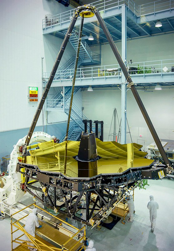 O espelho primário do Webb, formado por 18 segmentos hexagonais de berílio e cobertos por uma fina camada de ouro. No topo vê-se ainda o espelho secundário. Os técnicos de NASA Goddard ajudam a perceber a escala. Credit: NASA/Chris Gunn.